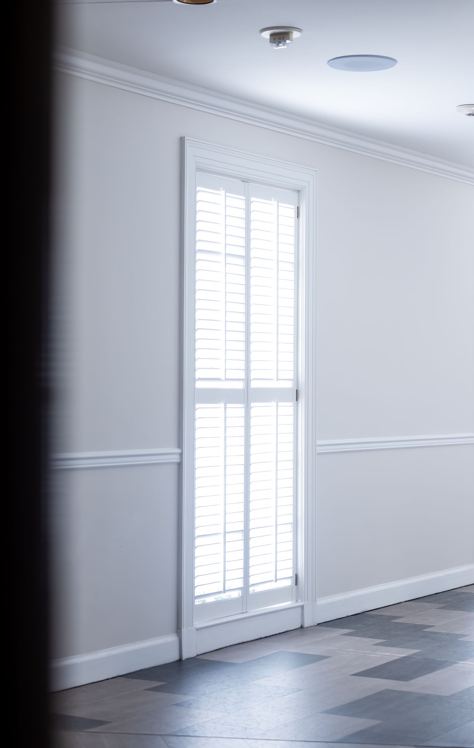 Custom white plantation shutters on a tall window in a Tallahassee home
